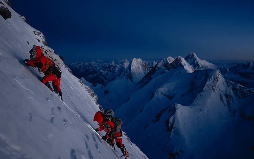 Two mountain climbers ascend at night